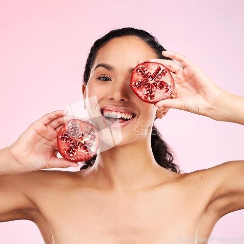 Image of Woman, skincare portrait and pomegranate for beauty, natural cosmetics and facial product or vitamin c benefits. Face of person, red fruits and eye dermatology or skin care on pink, studio background