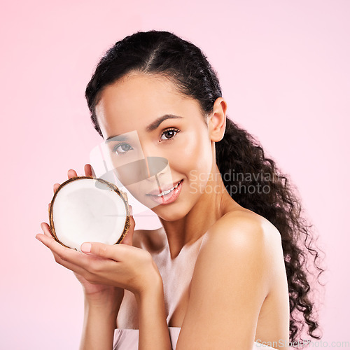 Image of Woman, portrait and coconut fruit skincare, beauty or vegan cream on pink studio background. Face of african person for natural product and eco friendly dermatology, healthy cosmetics or oil benefits