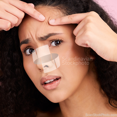 Image of Skincare, woman and squeeze pimple or problem with natural beauty in pink studio background. Face, check and girl with acne or blackhead for dermatology for cosmetic or wellness with self care.