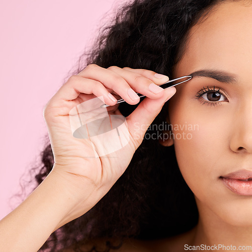 Image of Face, beauty and woman with tweezer for eyebrow, skincare and grooming isolated on a pink background. Natural portrait, facial plucking and hair removal of serious model for wellness and aesthetic