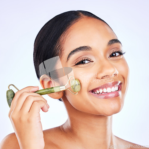 Image of Facial roller, natural beauty and woman massage skin for wellness and glow. Portrait of a young aesthetic female model happy with dermatology, self care and face tools results on a studio background