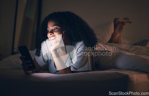 Image of Happy woman, phone and relax in bed at night for social media, online browsing or streaming at home. Female person smile on mobile smartphone app in the dark late evening for entertainment in bedroom