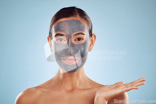 Image of Face mask, skincare and beauty of woman showing facial product isolated in blue studio background. Skin, charcoal and person palm as advertising, branding or marketing hydration and clean dermatology