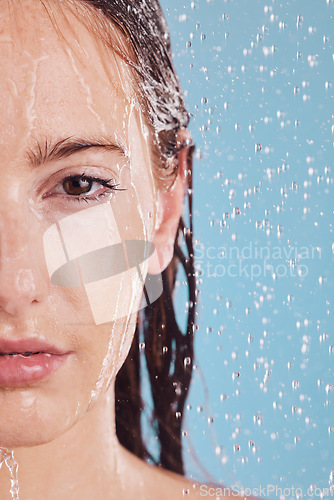 Image of Closeup, portrait and woman with water, shower or hygiene on a blue studio background. Face, female person or model with drops, liquid or aqua for washing, cleaning or morning routine with wellness