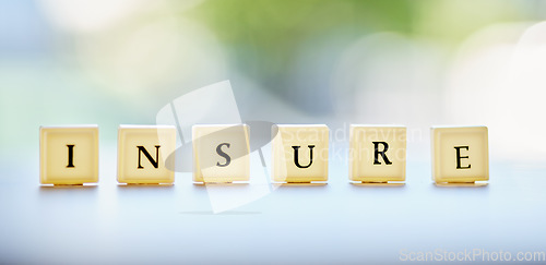 Image of Letters, blocks and an insurance message on a desk for business, security or finance with bokeh. banner, mockup and a word on a table at a financial company for profit, investment or savings