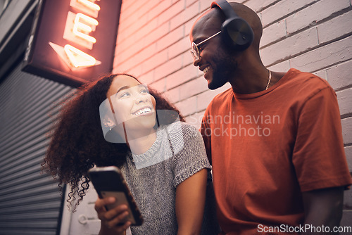 Image of Phone, music and headphones with an interracial couple outdoor in a city together for dating. Love, mobile app or streaming with a man and woman bonding in an urban town while listening to the radio