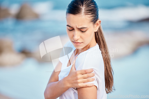 Image of Woman, fitness and arm pain on beach from workout injury, exercise or outdoor accident. Female person with sore shoulder, joint ache or inflammation and muscle tension after exercise on ocean coast