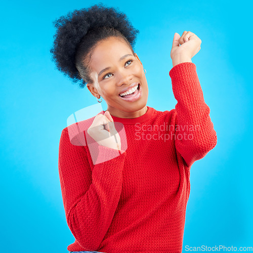 Image of Happy woman, fist pump and celebration for winning, discount or sale against a blue studio background. Excited female person for good news, bonus promotion or lottery prize in reward or competition