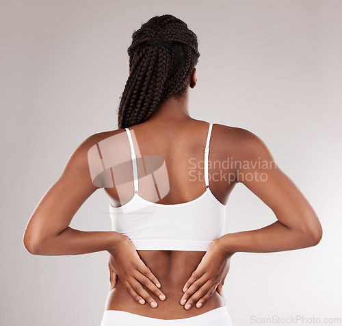 Image of Back pain, hands and body of black woman in underwear isolated on a white background in studio. Spine problem, injury and African model in lingerie with arthritis, muscle fibromyalgia or osteoporosis