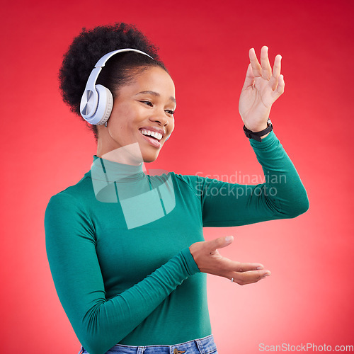 Image of Happy, dance and black woman with music headphones in studio, freedom and good mood on red background. Podcast, radio and African female with earphone streaming, dancing and celebrating vibes