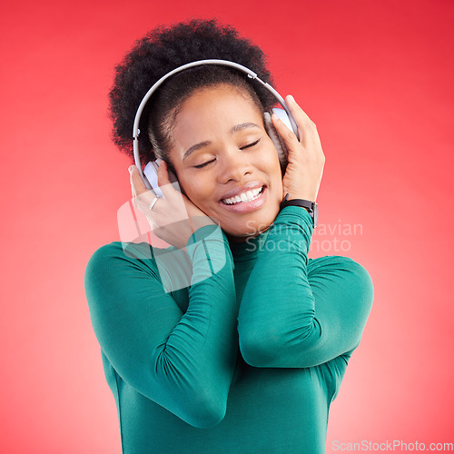 Image of Happy black woman, headphones and listening to music for audio streaming against a red studio background. Calm African female person smile in relax enjoying sound track or entertainment on headset