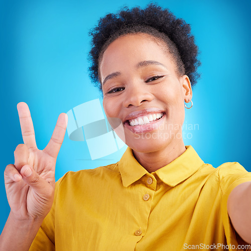 Image of Happy woman, portrait smile and peace sign for selfie, photography or memory against a blue studio background. African female person or photographer for picture, photo or online social media post