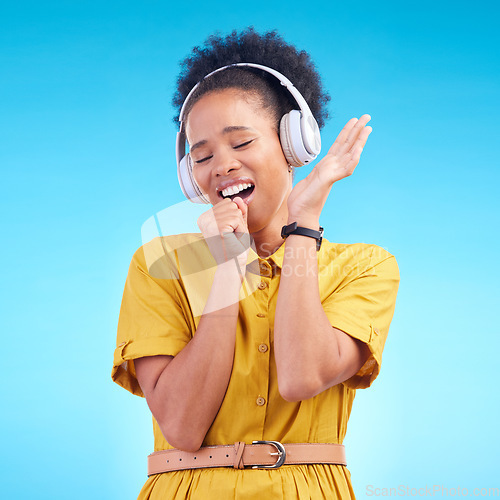 Image of Happy woman, headphones and singing while listening to music for karaoke against a blue studio background. Female person enjoying audio sound track or song with headset for entertainment on mockup