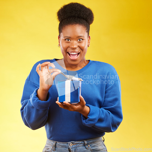 Image of Gift, present and portrait of black woman with a surprise happy isolated in a yellow studio background for a birthday. Shocked, box and excited person to celebrate, party and holiday as a winner