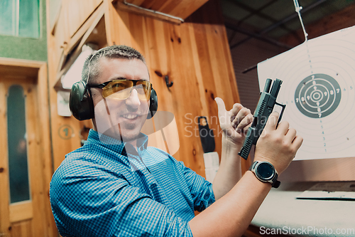 Image of A man practices shooting a pistol in a shooting range while wearing protective headphones