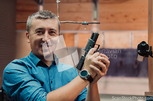 Image of A man practices shooting a pistol in a shooting range while wearing protective headphones