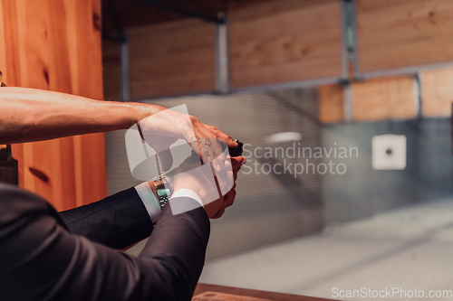 Image of A man practices shooting a pistol in a shooting range while wearing protective headphones