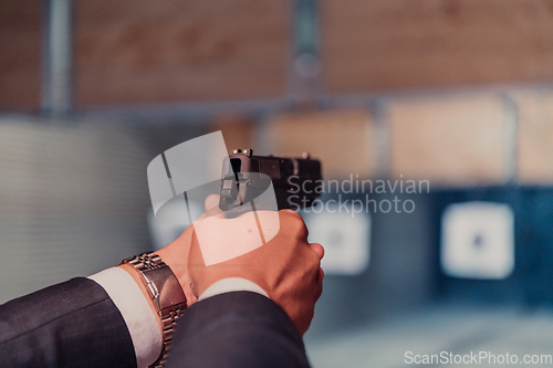 Image of A man practices shooting a pistol in a shooting range while wearing protective headphones