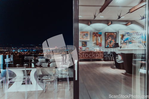 Image of A beautiful house with a beautiful view of the night city. Luxury living room and tereasa with a view of the city. Night photo of a luxury house