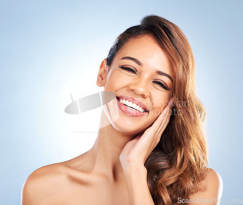 Image of Happy woman, portrait and face in skincare for beauty, haircare or cosmetics against a blue studio background. Female person or model touching perfect skin in satisfaction for spa or facial treatment