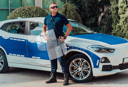 Image of A policeofficer patrols the city. A police officer with sunglasses patroling in the city with an official police car