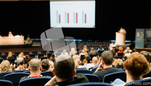 Image of Speaker giving a talk in conference hall at business event. Rear view of unrecognizable people in audience at the conference hall. Business and entrepreneurship concept.