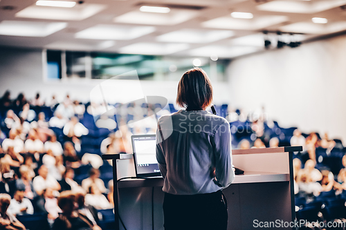 Image of Female speaker giving a talk on corporate business conference. Unrecognizable people in audience at conference hall. Business and Entrepreneurship event.