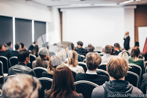 Image of Speaker giving a talk in conference hall at business event. Rear view of unrecognizable people in audience at the conference hall. Business and entrepreneurship concept.