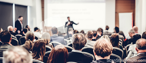 Image of Speaker giving a talk in conference hall at business event. Rear view of unrecognizable people in audience at the conference hall. Business and entrepreneurship concept.