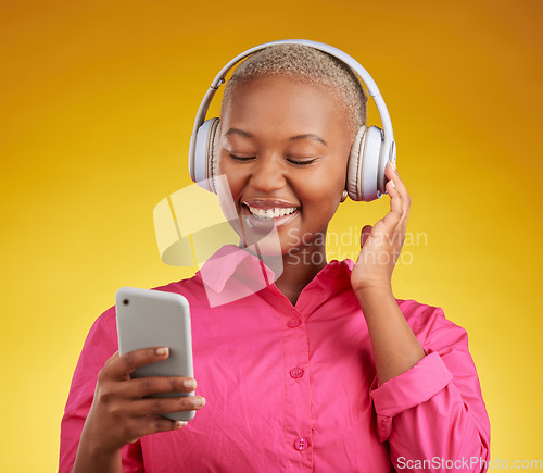 Image of Happy, phone and black woman with music headphones in studio for streaming, track or selection on yellow background. Radio, podcast and African lady online with smartphone for audio subscription app