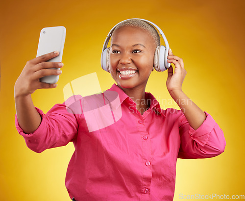 Image of Smile, selfie and black woman with headphones for music, radio and podcast in studio isolated on a yellow background. Profile picture, photographer and African person or influencer on social media