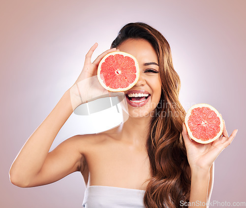 Image of Vitamin c, grapefruit and portrait of woman with healthy, natural or organic beauty isolated in a brown studio background. Excited, happy and young female person with citrus for skincare or detox