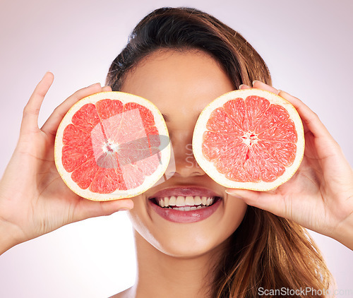 Image of Beauty, grapefruit and eyes of woman with healthy, natural or organic care isolated in a brown studio background. Citrus, happy and young female person with vitamin c for skincare, wellness or detox