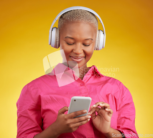 Image of Phone, smile and black woman with music headphones in studio for streaming, track or selection on yellow background. Radio, podcast and African female online with smartphone for audio subscription