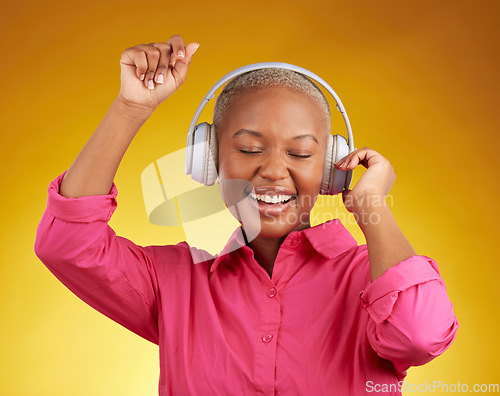 Image of Music headphones, smile and black woman dancing in studio isolated on a yellow background. African person, happy and listening to radio, jazz or streaming audio, podcast and hearing sound with energy