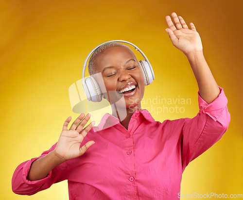Image of Happy, music headphones and black woman dance in studio isolated on a yellow background. African person, smile and listen to radio, singing and streaming audio, podcast or hearing sound with energy