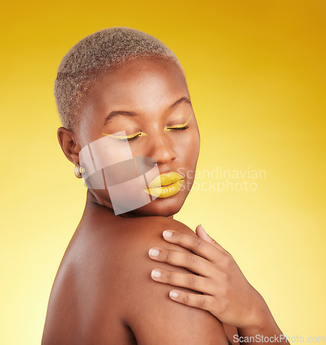 Image of Beauty, cosmetic and young woman in a studio with eyeliner and lipstick for cosmetology. Self care, makeup and creative African female model with a colorful glamour face routine by yellow background.