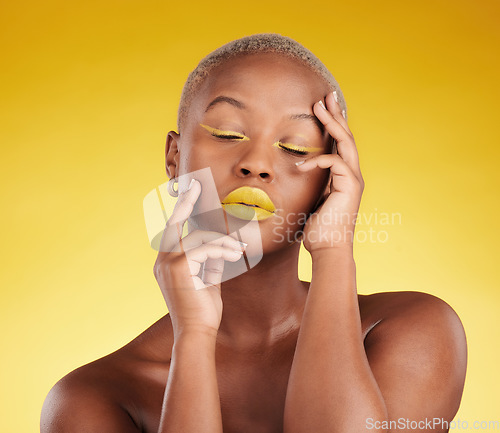 Image of Creative, makeup and face with lipstick or black woman in studio on a yellow background for art, beauty or cosmetics. Gold, color and eyeshadow on calm model with eyes closed for fashion or aesthetic