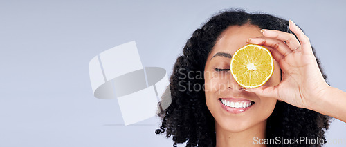 Image of Skincare, wellness and woman with lemon eye or fruit for nutrition in grey studio background or banner. Dermatology, hand and smile with girl or vitamin c for natural facial or diet in mockup space.