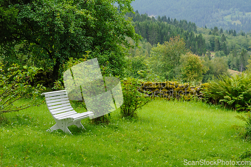 Image of white bench in old garden with mossy stone fence