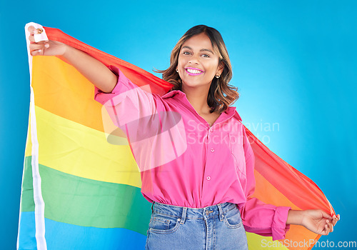 Image of Lgbtq flag, portrait and woman with support, pride and happiness on a blue studio background. Female person, ally or model with symbol for queer community, equality or transgender rights with freedom