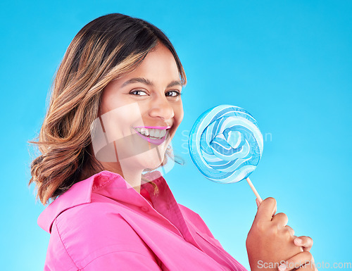 Image of Woman, lollipop and smile in studio portrait with eating, sweets and excited for food by blue background. Girl, student or young fashion model with candy, beauty or happy with sugar for dessert snack