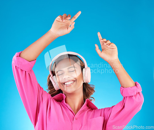 Image of Woman, student headphones and happy music for audio streaming service or mental health podcast in studio. Young person dance or listening to radio for wellness and excited on a blue background