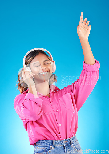 Image of Happy woman, headphones and listening to music, audio streaming service and techno or student podcast in studio. Young person dance to radio for wellness and electronics on a blue gradient background