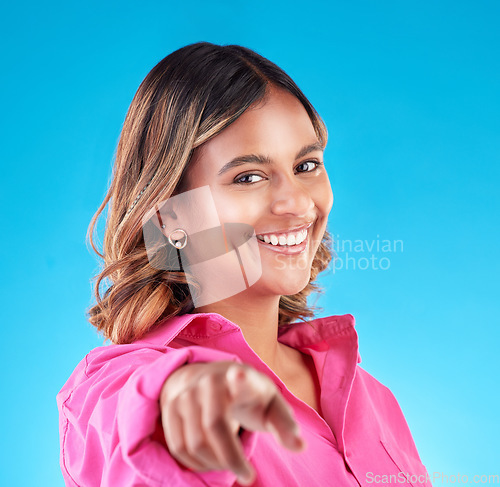 Image of Pointing finger, smile and portrait of woman in studio to select, advertising or choice. Face of happy model person with hand or emoji for accountability, decision or choosing you on blue background