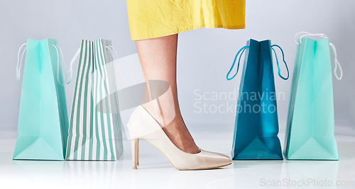 Image of Shopping bag, shoes and a woman in studio for fashion sale, promotion or retail discount. Feet of a female model or customer on a white background advertising commerce offer, high heels or gift