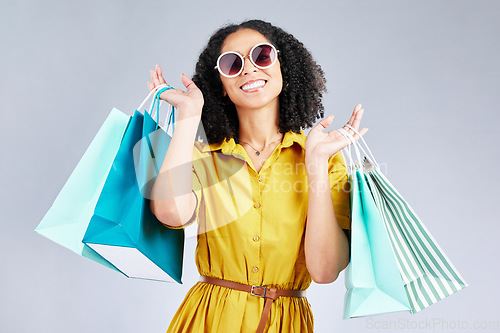 Image of Portrait, sunglasses and woman smile with shopping bag for fashion in studio isolated on a white background. Cool, sales and African customer with gift, discount deal and stylish clothes from store