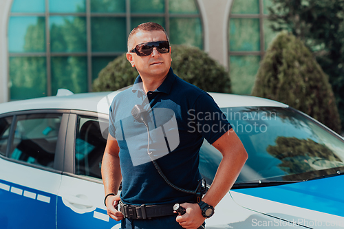 Image of A policeofficer patrols the city. A police officer with sunglasses patroling in the city with an official police car