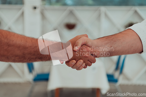 Image of Close up a handshake, businessman together creates a mutually beneficial business relationship. The economic graph on the table