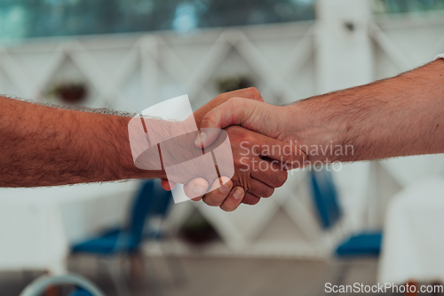 Image of Close up a handshake, businessman together creates a mutually beneficial business relationship. The economic graph on the table